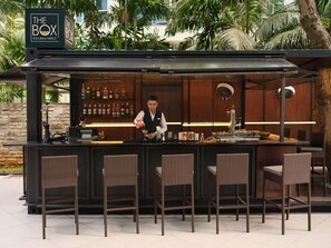 Zona de bar con un letrero que dice 'The Box' y un bartender preparando una bebida.