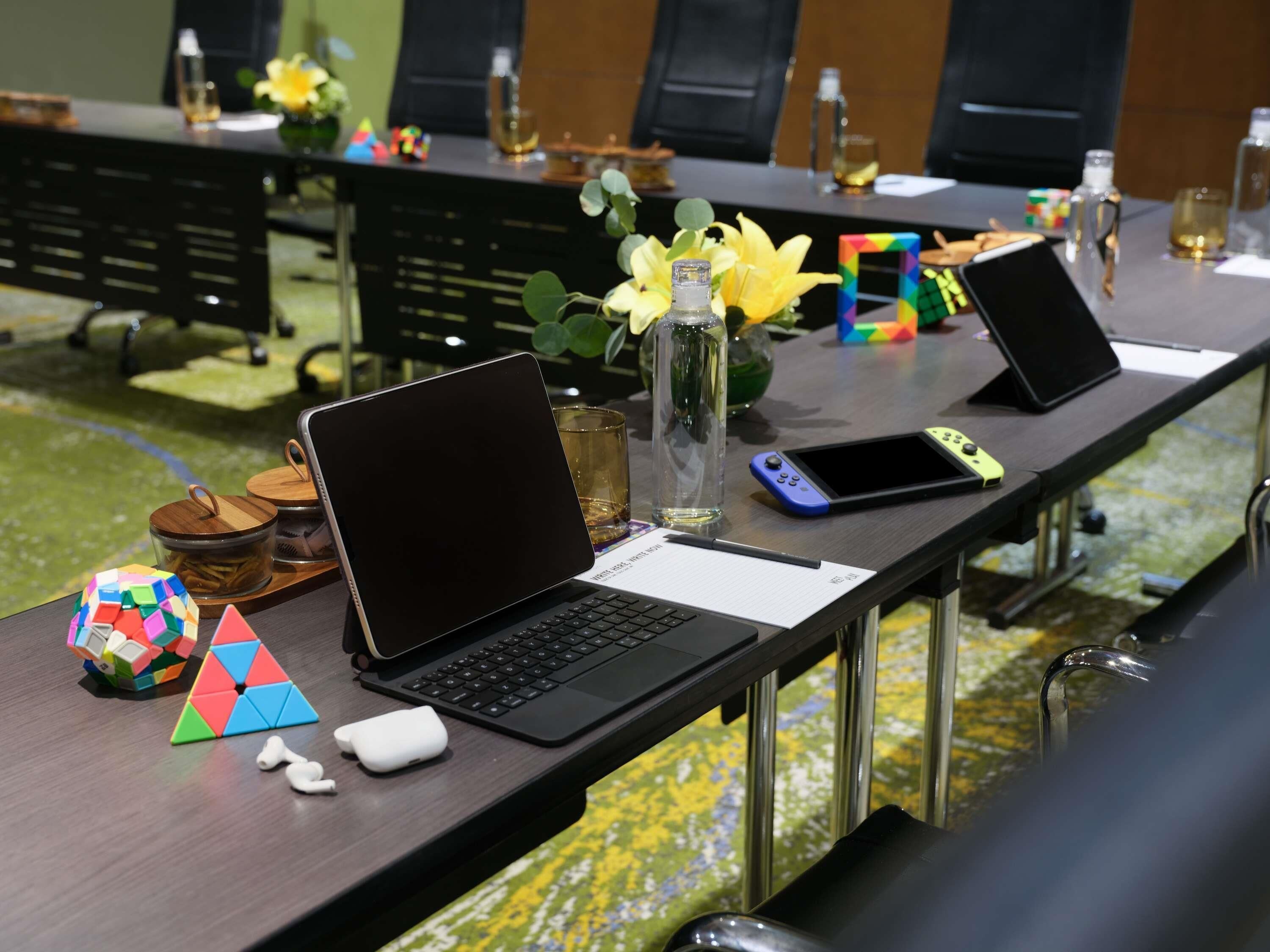 A conference table with laptops, a smartphone, a water bottle, and a puzzle cube.