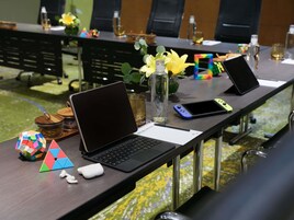 A conference table with laptops, a smartphone, a water bottle, and a puzzle cube.