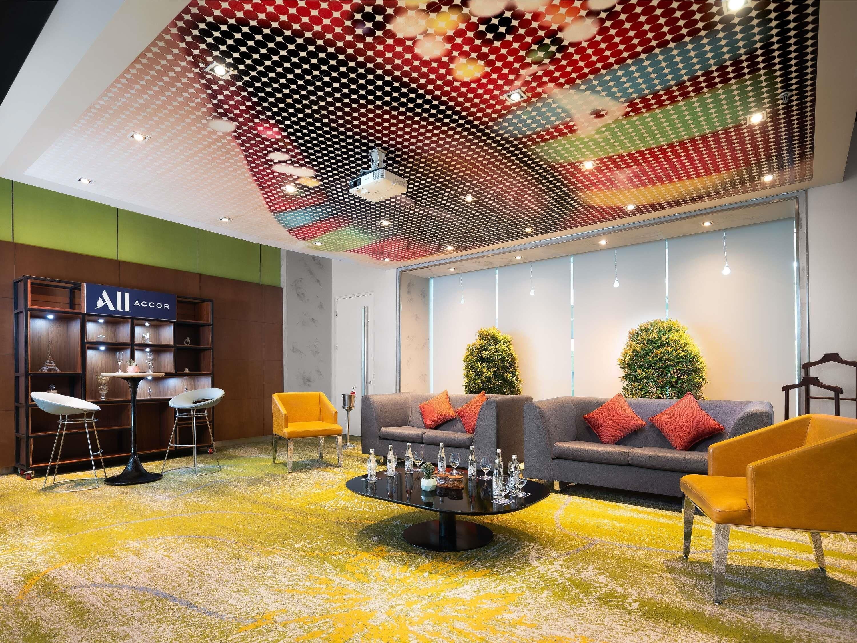 A modern lobby with a digital ceiling display, a reception desk, seating area, and a green wall.