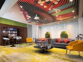 A modern lobby with a digital ceiling display, a reception desk, seating area, and a green wall.