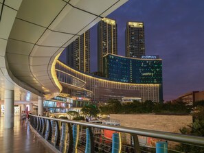 Un hotel moderno con fachada curva, un llamativo letrero 'Pullman' y vistas de edificios altos aledaños.