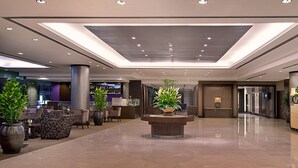 A spacious lobby with a reception desk, seating area, and a central planter with plants. - Furama Bukit Bintang (Kuala Lumpur)