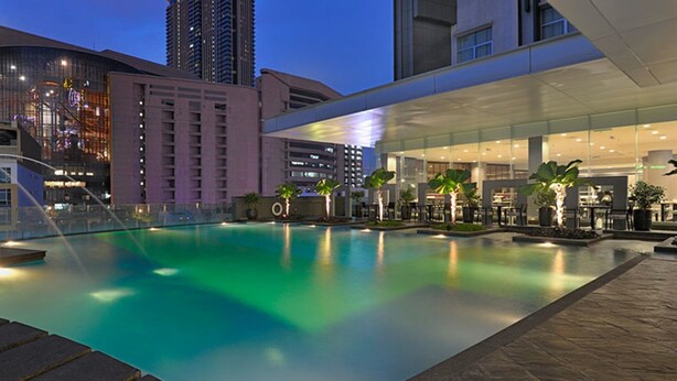 A modern hotel with a rooftop pool, surrounded by high-rise buildings and a well-lit outdoor area. - Furama Bukit Bintang (Kuala Lumpur)