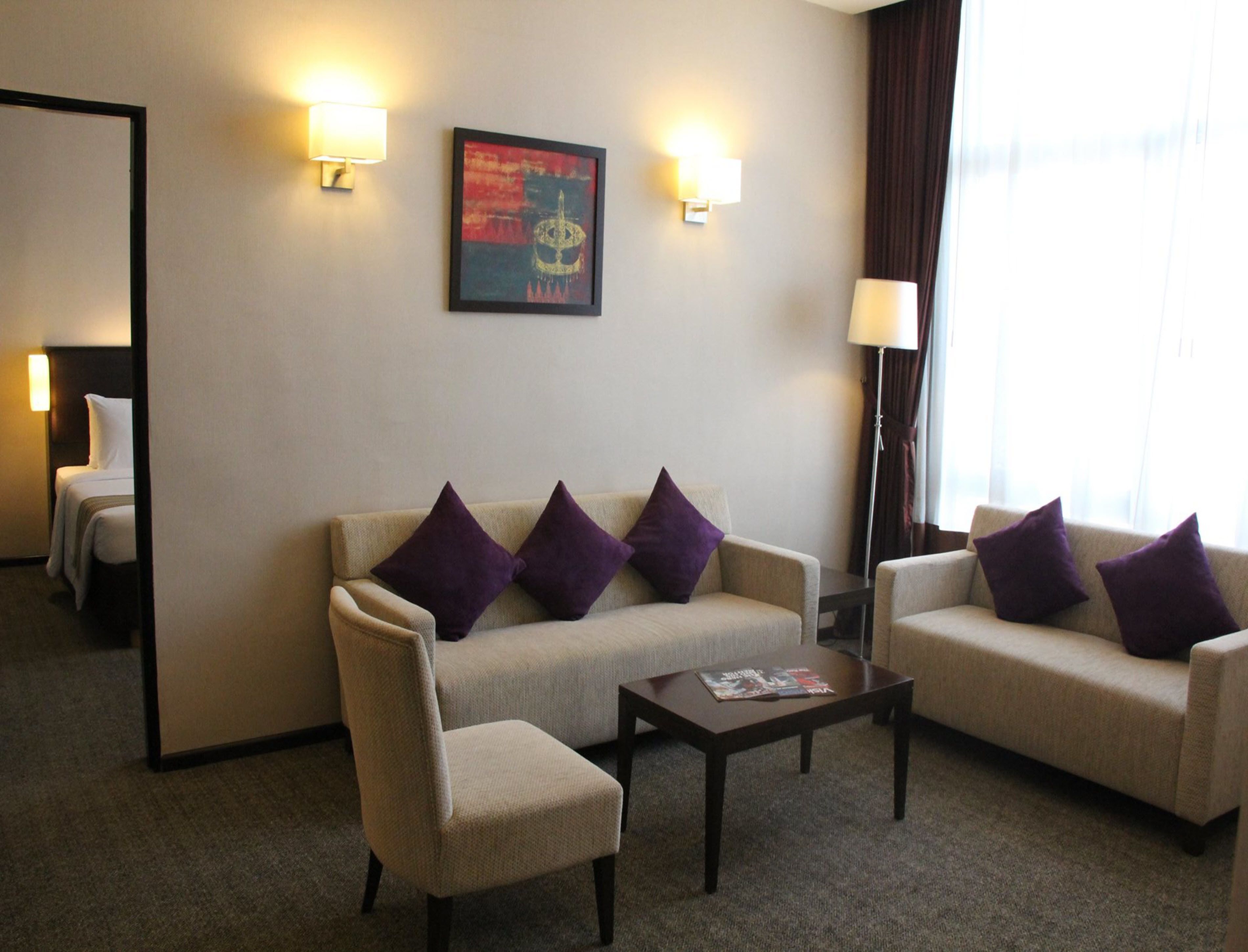 A hotel room with a sofa set, a coffee table, and a framed artwork on the wall.