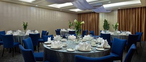 A conference room with round tables, blue chairs, and white table settings.