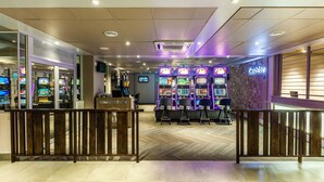 A casino interior with slot machines, a cashier, and a wooden railing.