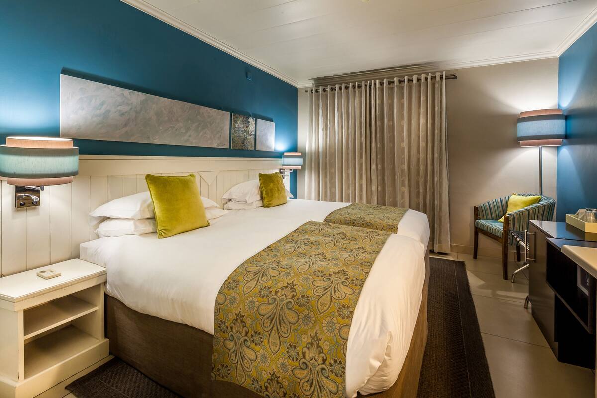 A hotel room with two beds, a desk, and a chair.