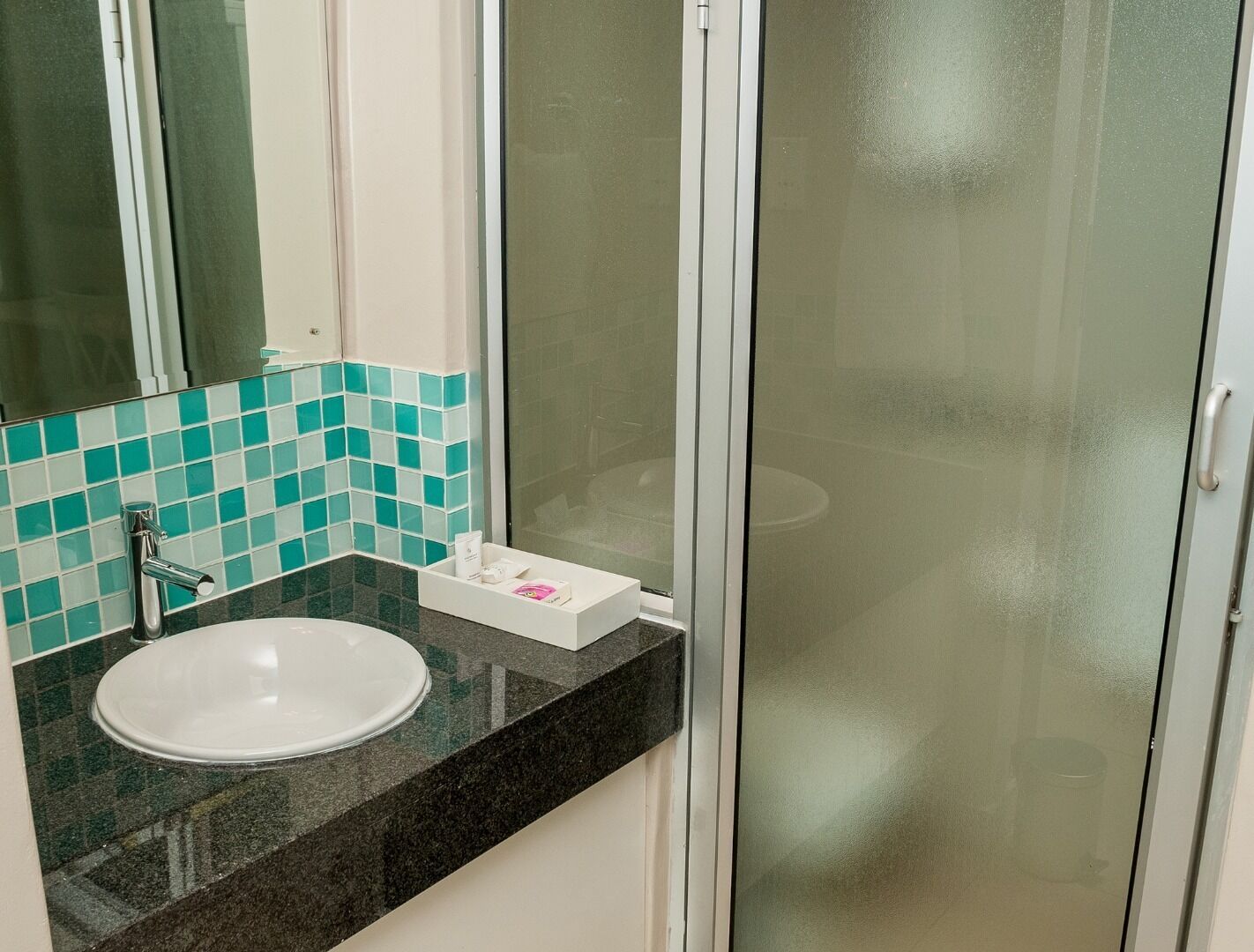 A bathroom with a white sink, a mirror, and a glass shower enclosure.