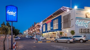 A Sedibeng Casino with a blue facade, Metcourt Lodge, and a parking lot with cars.