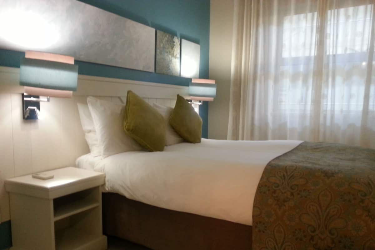 A hotel room with a bed, bedside table, and a nightstand.