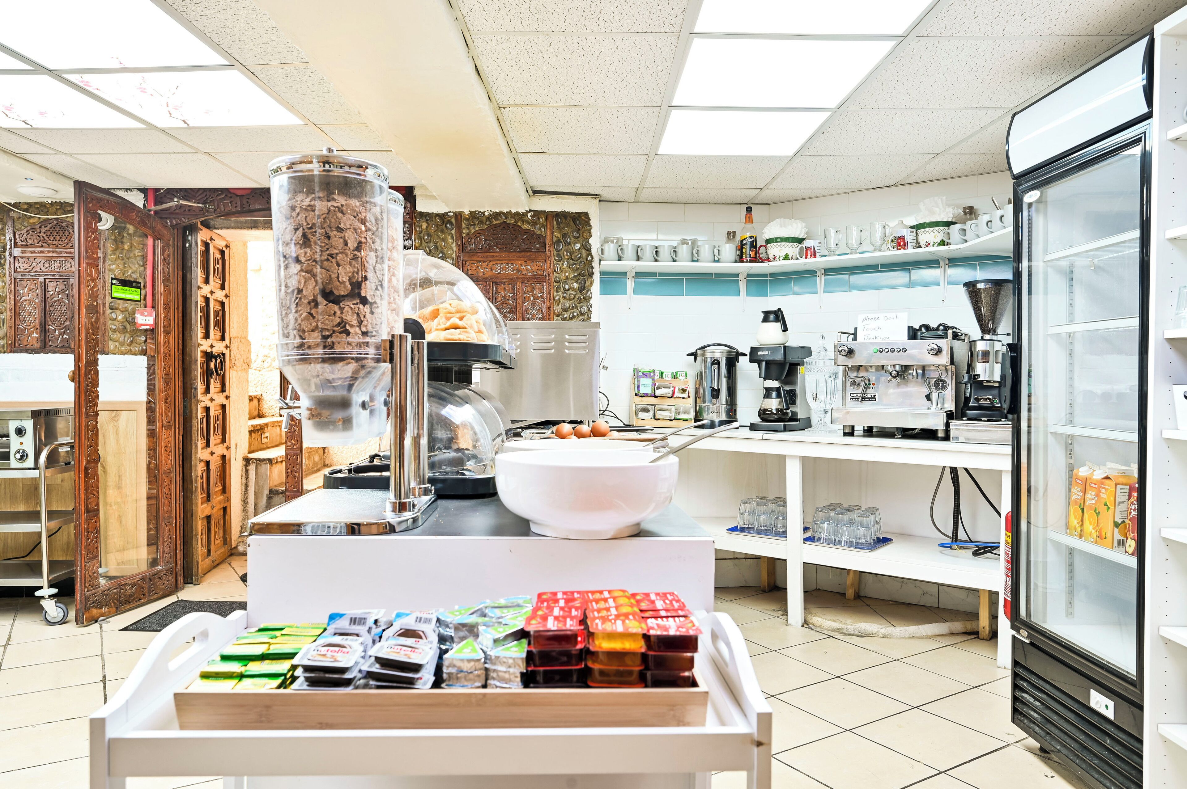 Um balcão de café da manhã com máquina de café, tigela de cereal e diversos alimentos embalados.