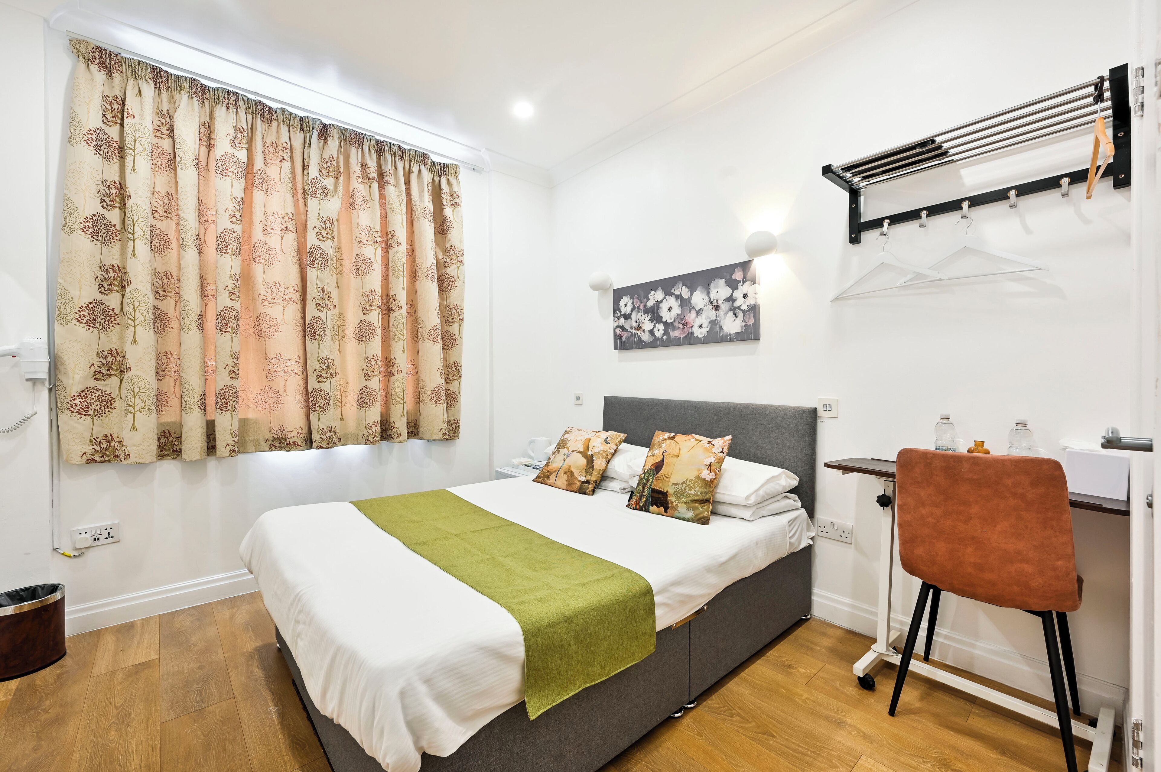 A neatly arranged bedroom with a bed, a desk, and a chair.