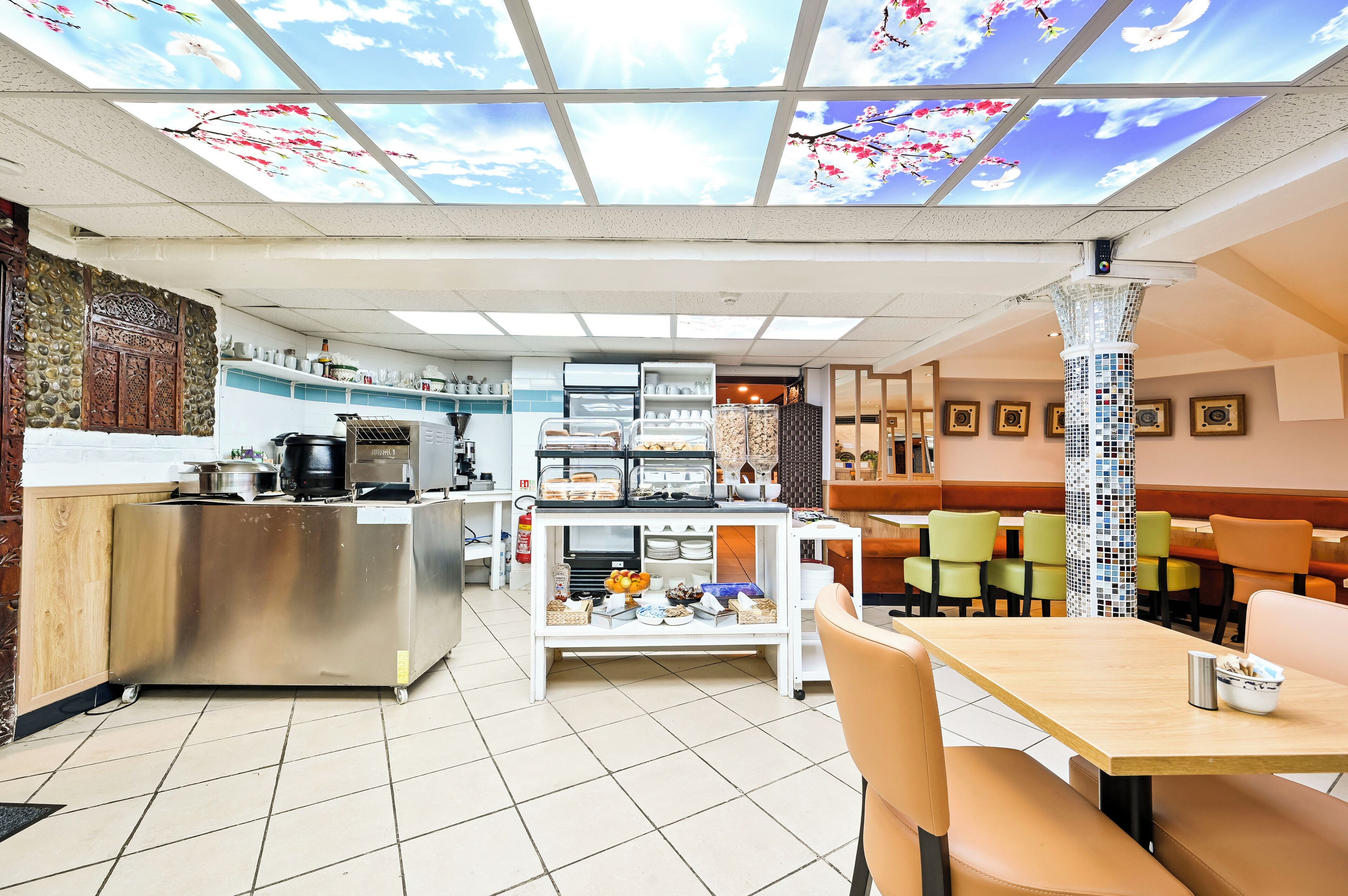 Un restaurante con zona de cocina, bufé y área de comedor.