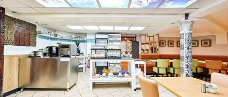 Un restaurante con zona de cocina, bufé y área de comedor.