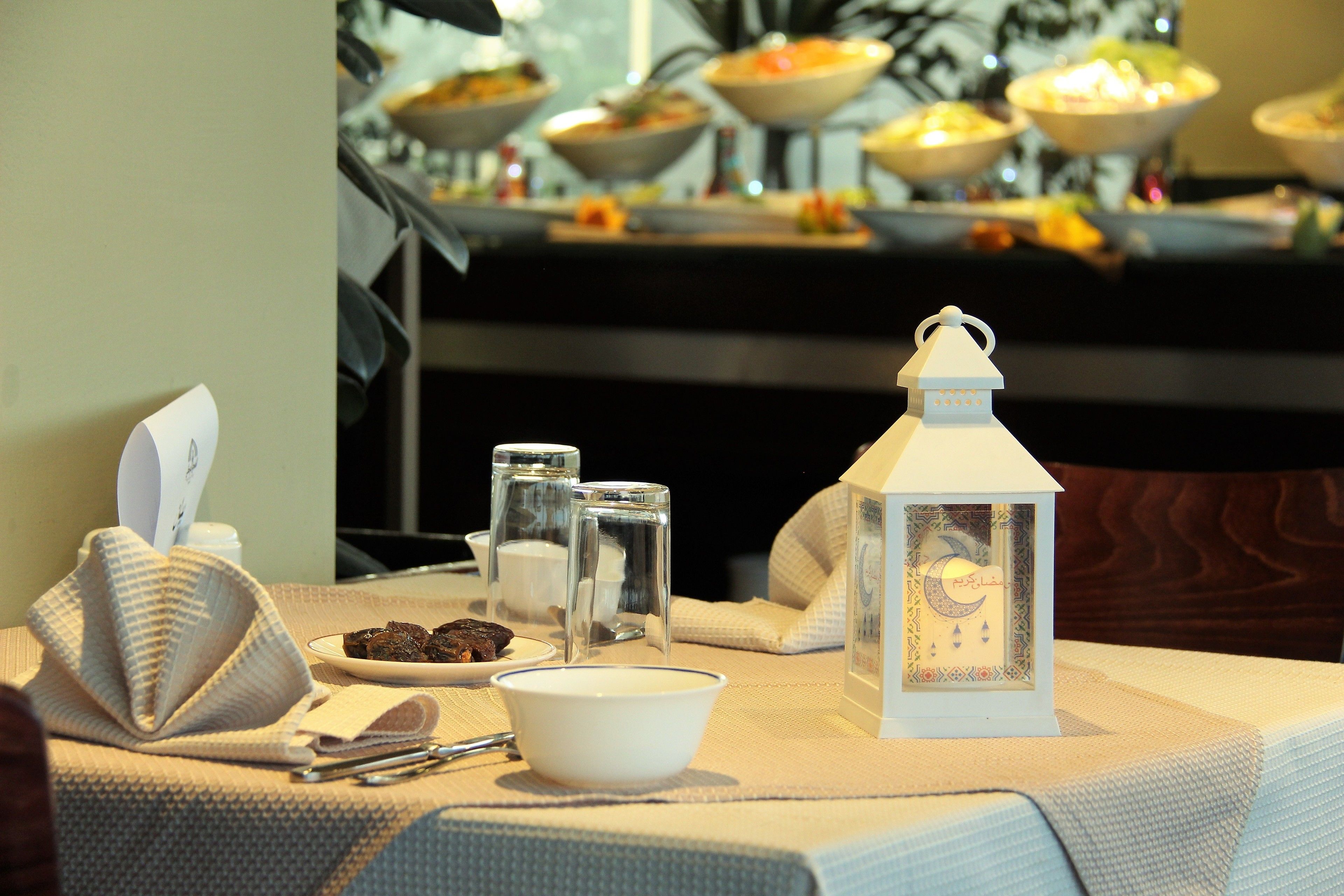 A table set with a white bowl, a white lantern, and a plate of cookies.
