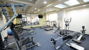 A gym with various exercise equipment, a large mirror, and a blue carpeted floor.