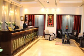 Un hall d’hôtel comprenant un comptoir d’accueil, un espace salon et des éléments de décoration.