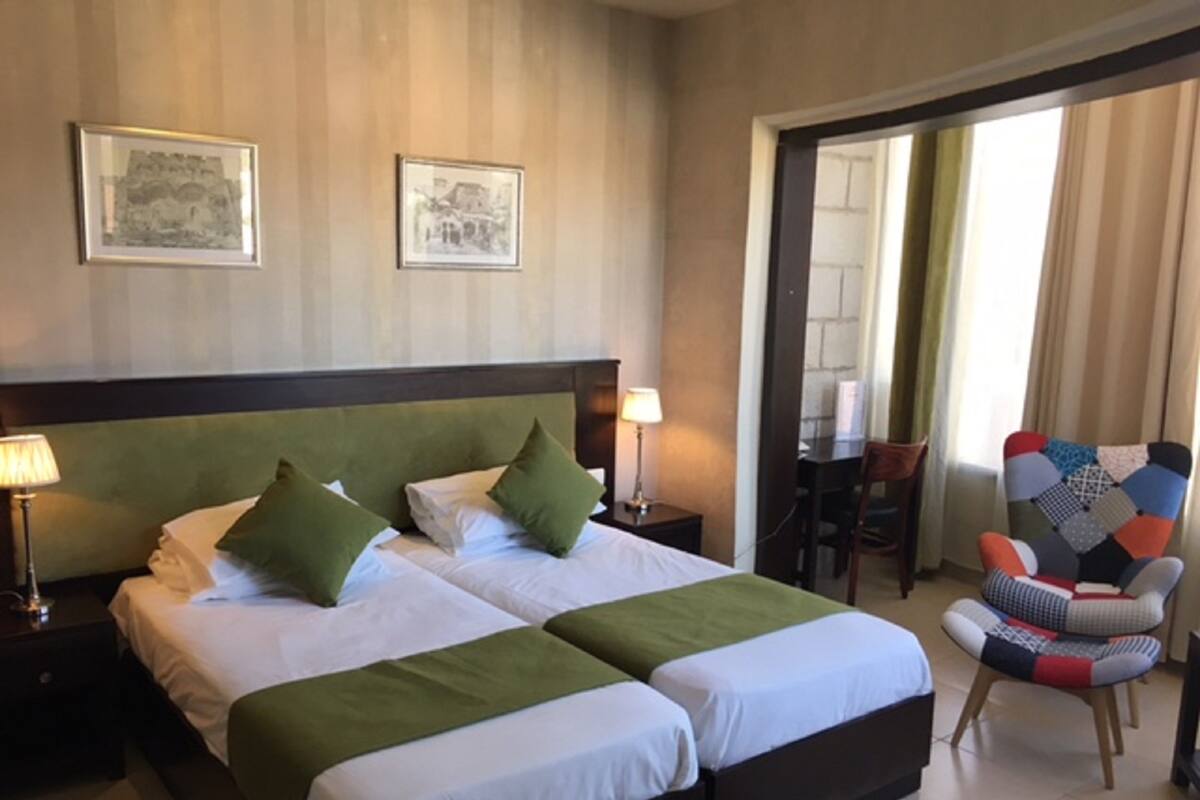A hotel room with a double bed, two bedside tables with lamps, a chair, and a desk.