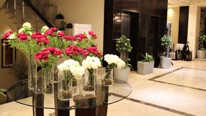 Un hall d’entrée avec une table en verre sur laquelle sont disposés des vases remplis de fleurs rouges et blanches.