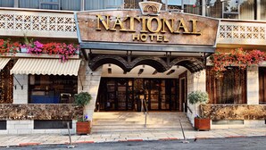 L’extérieur du National Hotel se distingue par son enseigne bien visible, son entrée abritée et ses plantes décoratives.