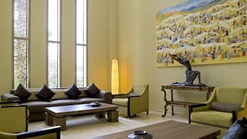 Ein geräumiges Wohnzimmer mit einer Sofagarnitur, Sesseln, einem Couchtisch und einem Gemälde an der Wand.