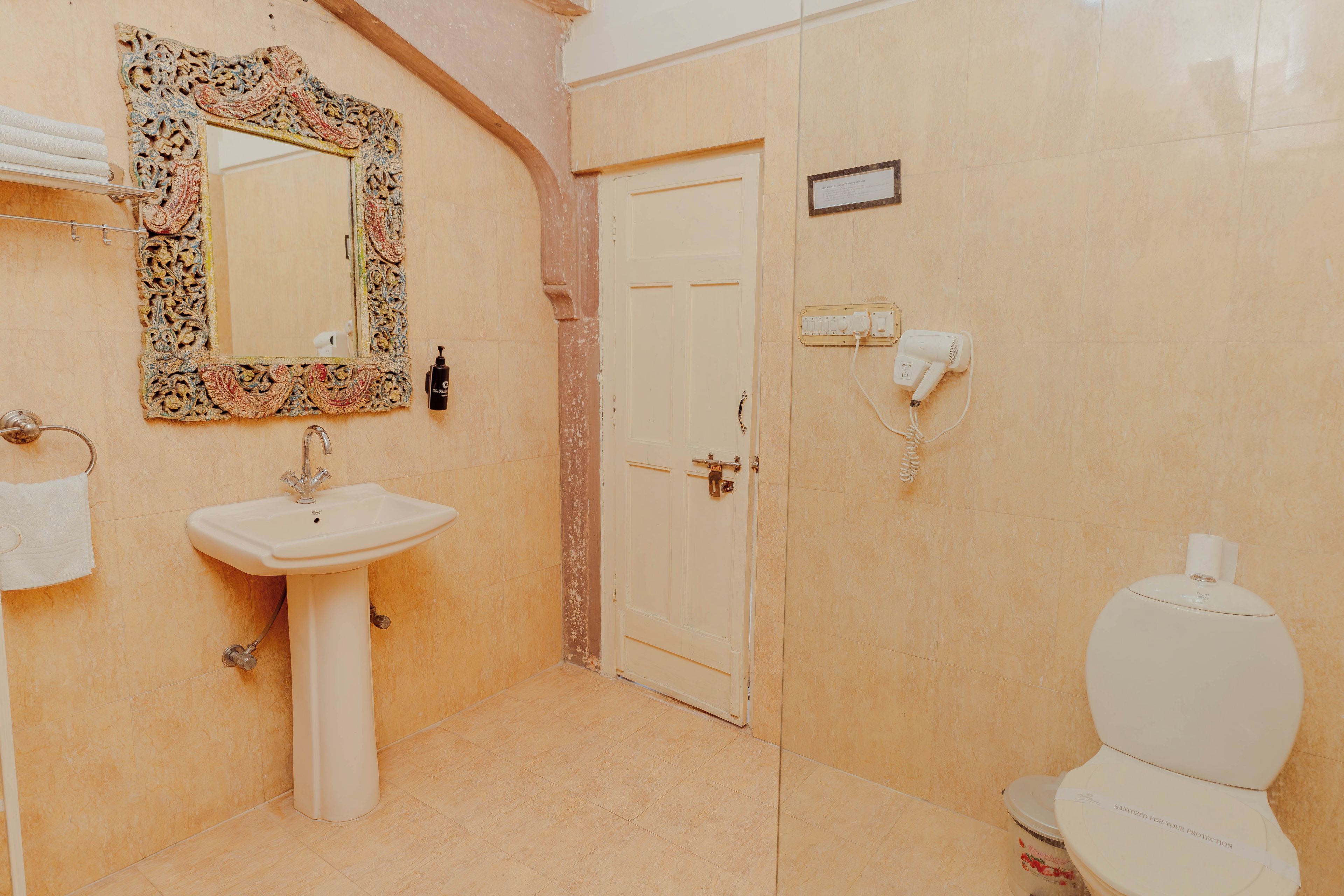 A bathroom with a sink, mirror, toilet, and a door.