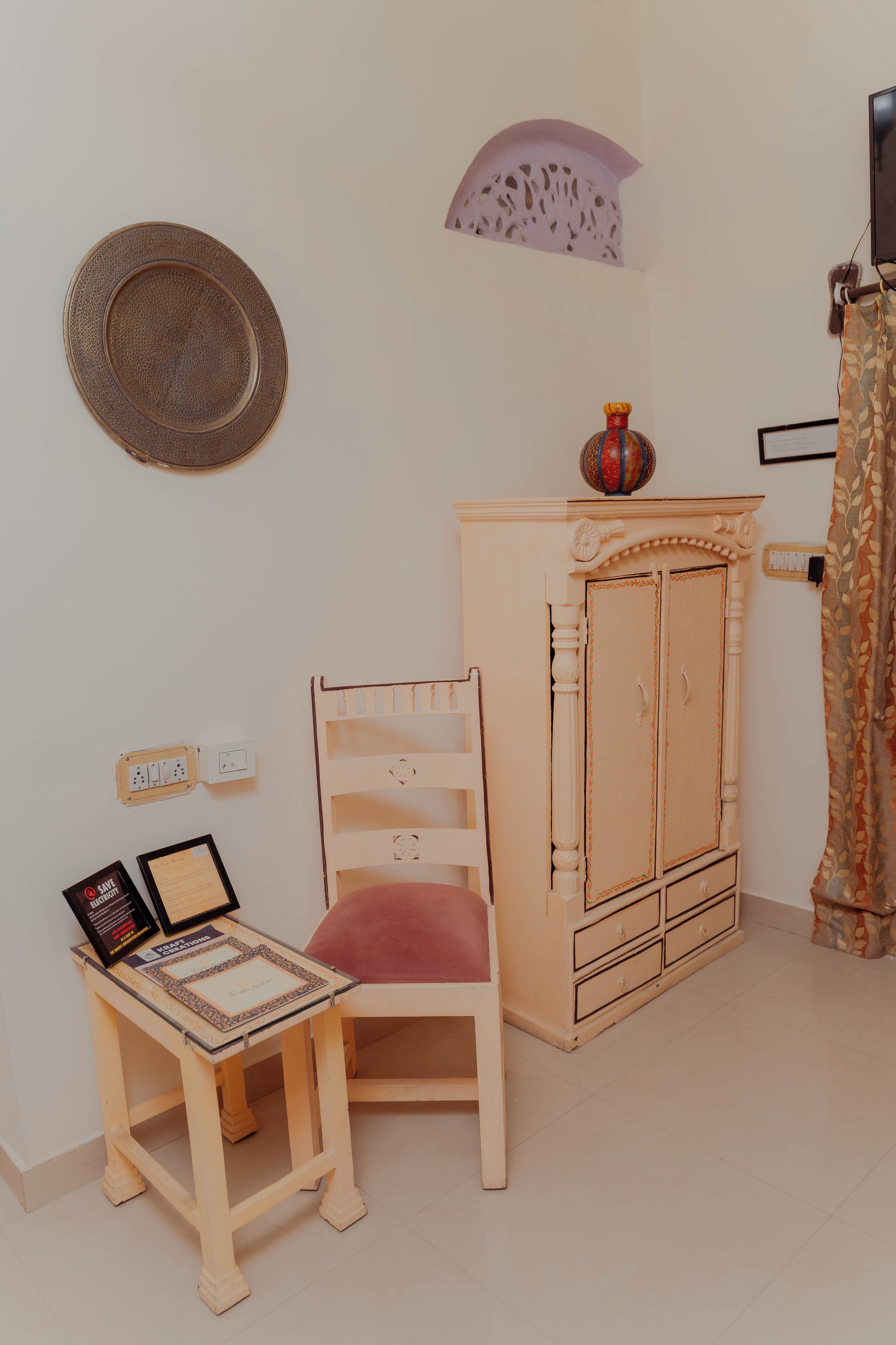 Une pièce comprenant une chaise en bois, une petite table avec un ordinateur portable, un meuble et un objet décoratif fixé au mur.