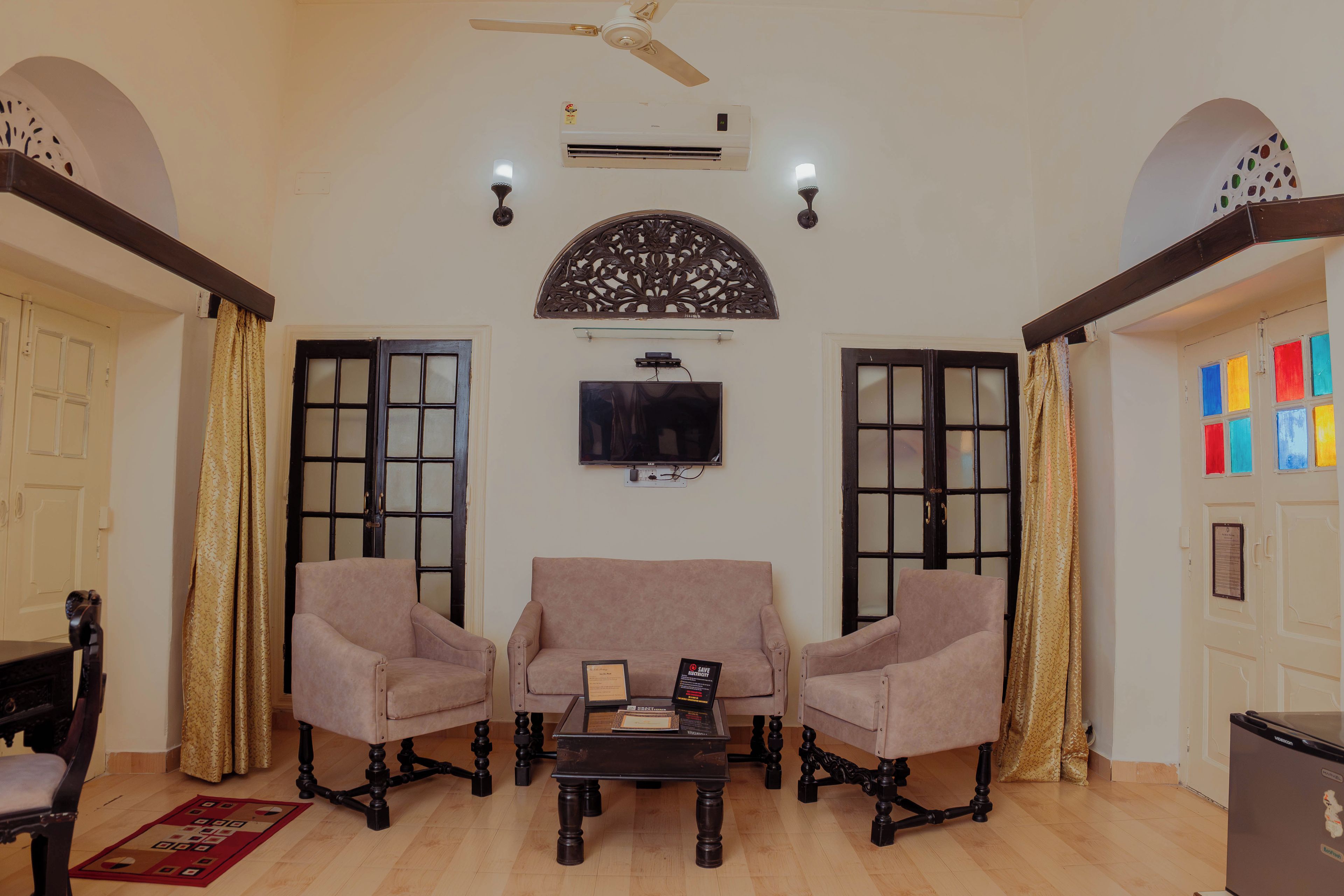 A living room with two armchairs, a coffee table, a flat-screen TV, and a ceiling fan.