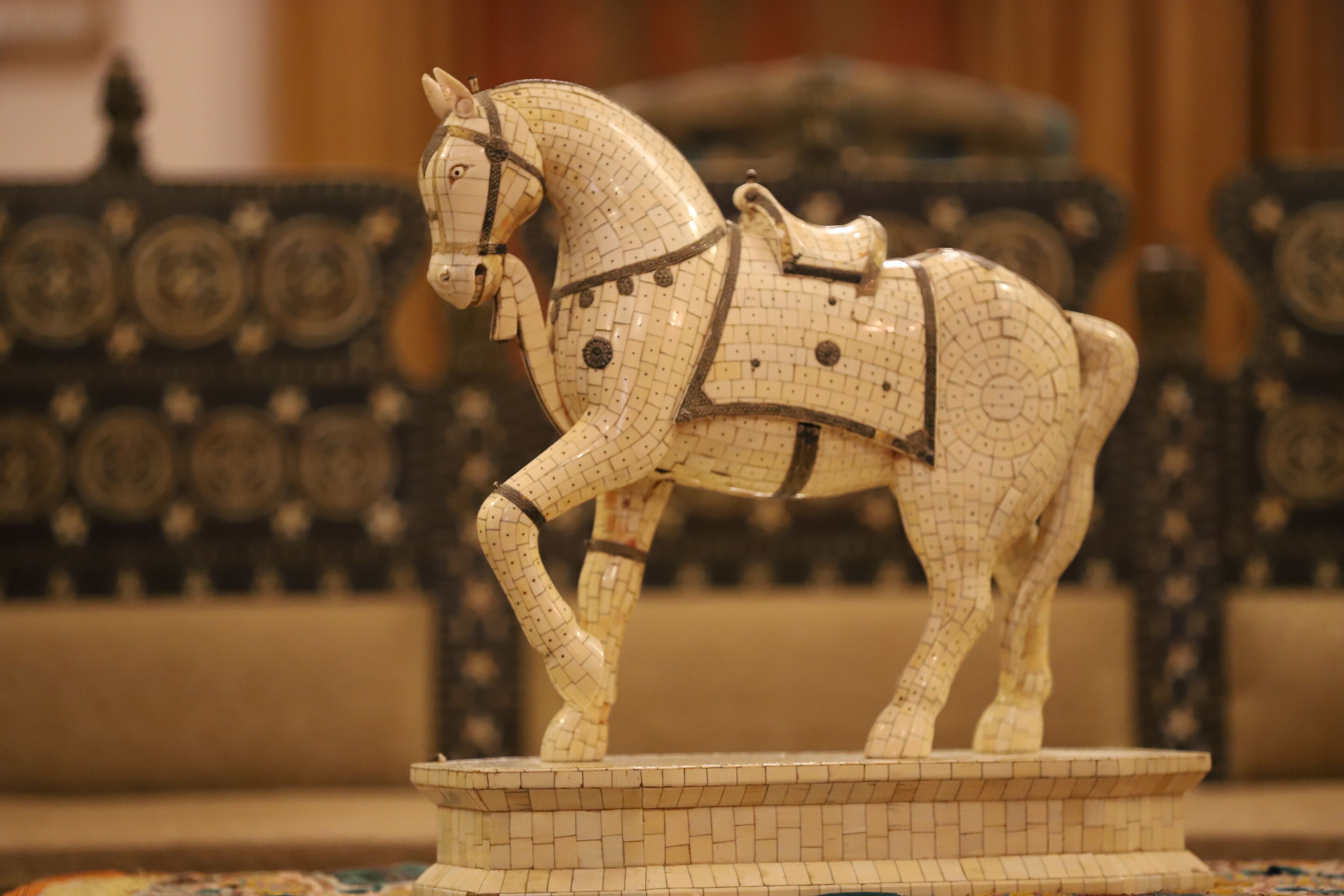 Una escultura de mosaico con forma de caballo sobre un pedestal.