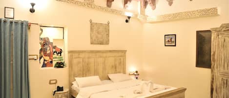A bedroom with a wooden bed, a nightstand, a wall-mounted lamp, and a mirror.