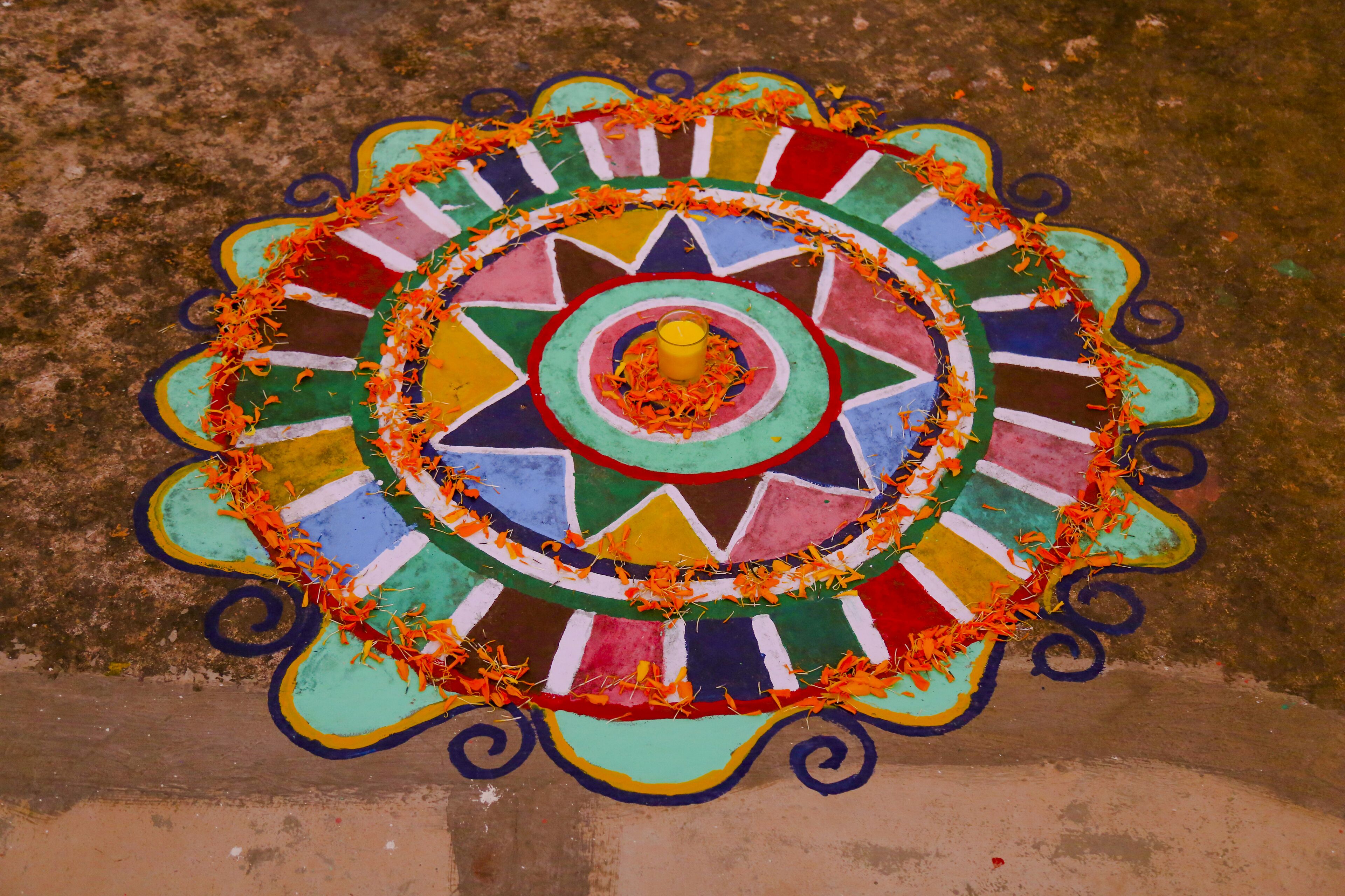 Un colorido diseño de rangoli sobre una superficie de concreto.