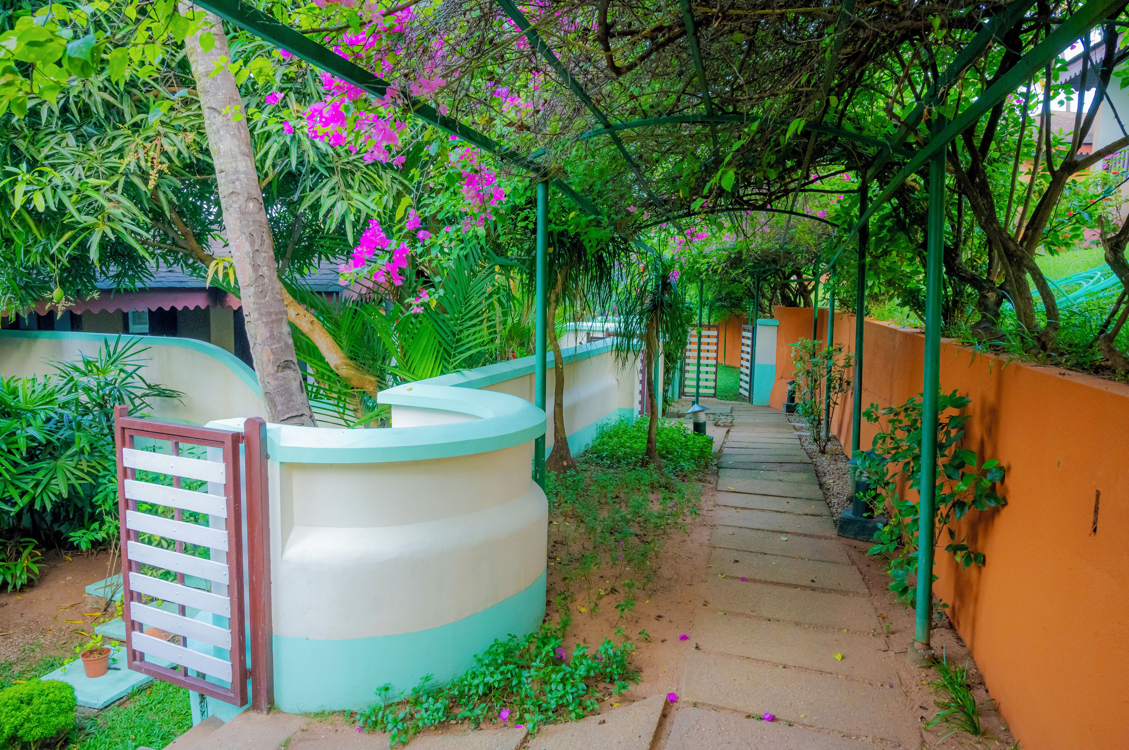 Un sendero que atraviesa un jardín con un muro curvo y una puerta.