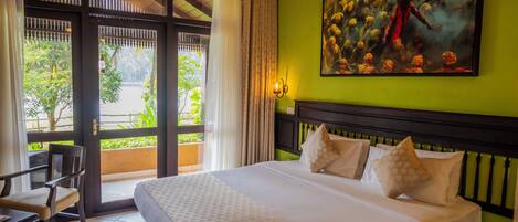 Une chambre d’hôtel avec un grand lit, un tableau au mur et une vue sur la verdure.