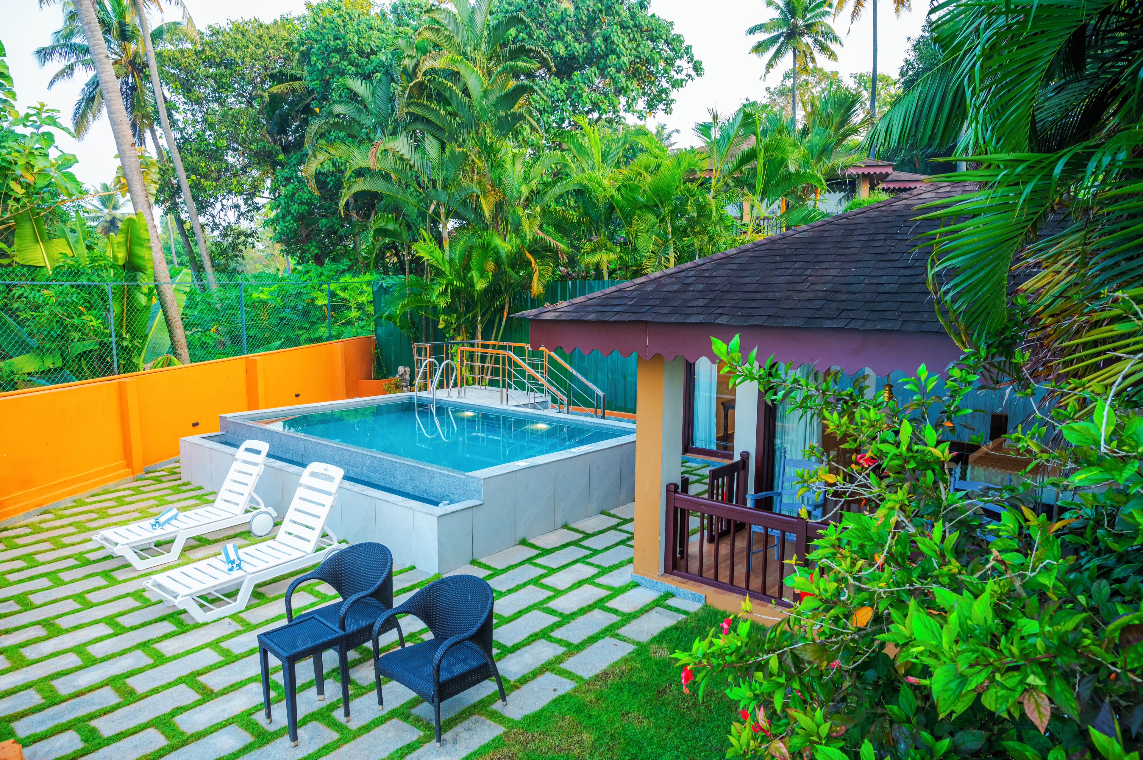 A swimming pool with lounge chairs and a small pavilion in a lush garden setting.
