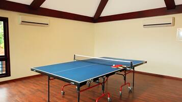 A ping pong table in a room with wooden flooring and a sloped ceiling.