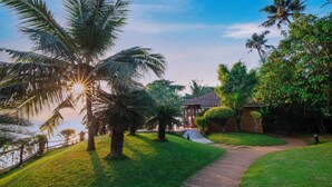 A pathway leading to a building surrounded by palm trees and greenery. - Fragrant Nature Backwater Resort & Ayurveda Spa (Kollam)