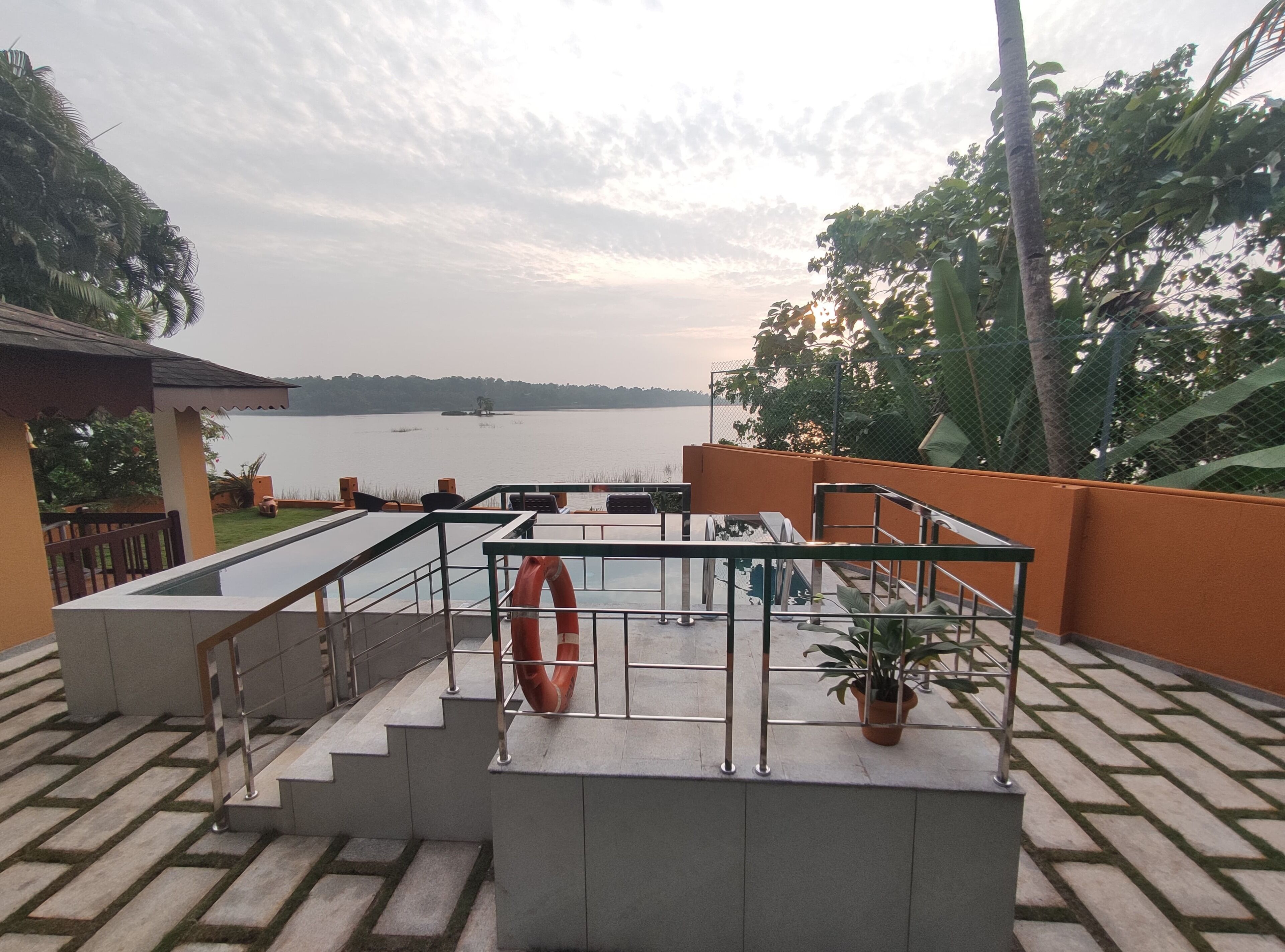 A terrace with a view of a lake, a lifebuoy, and a potted plant.
