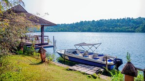A boat docked at a pier with a small structure nearby, surrounded by water and greenery. - Fragrant Nature Backwater Resort & Ayurveda Spa (Kollam)