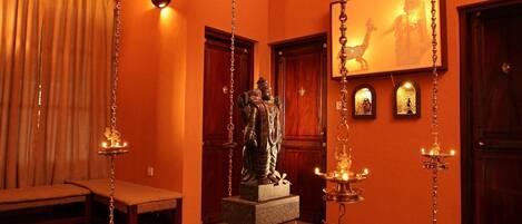 A room with a statue in the center, wooden benches, and a hanging light fixture.