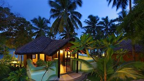 A resort with a thatched-roof structure, a pool, and lush tropical vegetation. - Fragrant Nature Backwater Resort & Ayurveda Spa (Kollam)