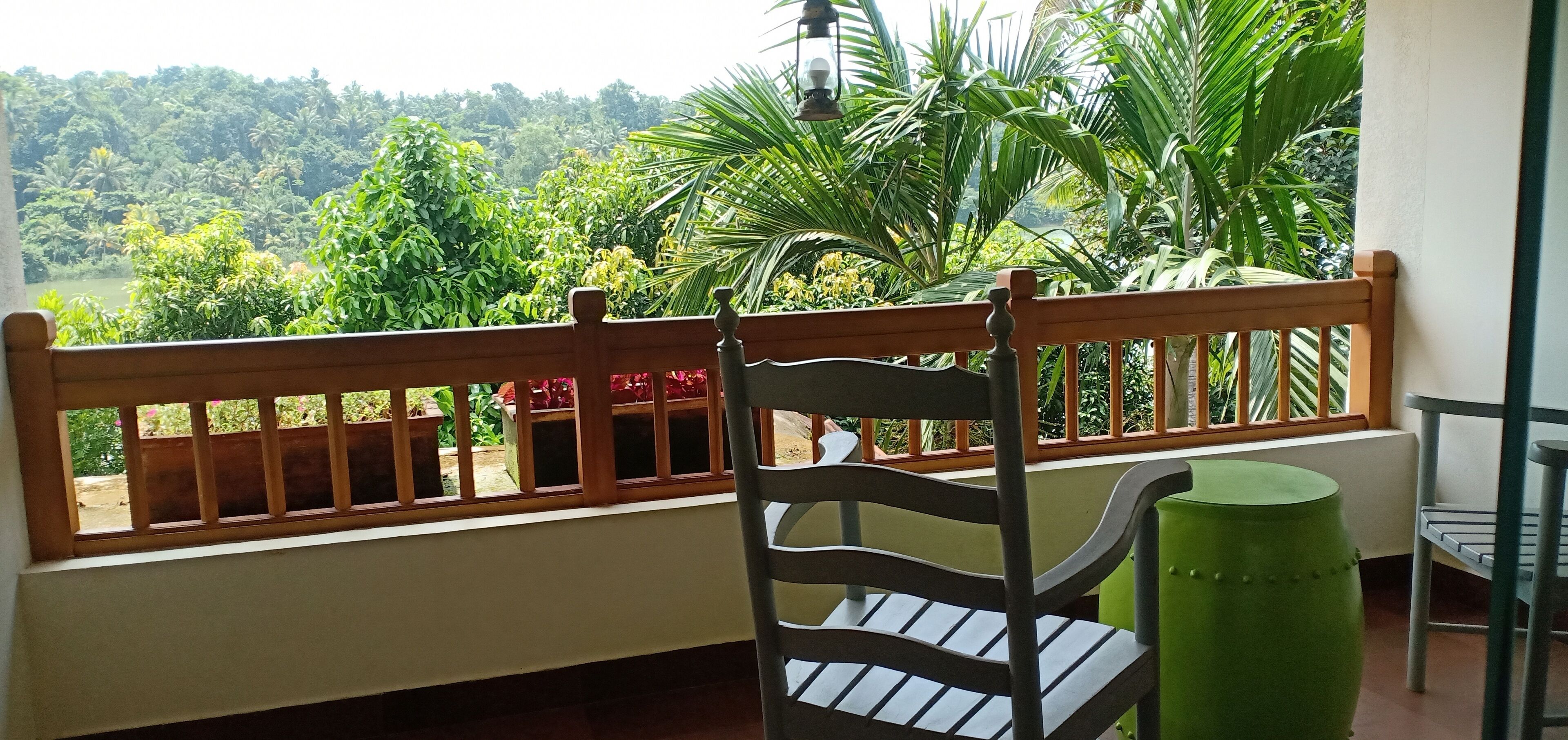 A balcony with a wooden railing, a chair, and a green pot.