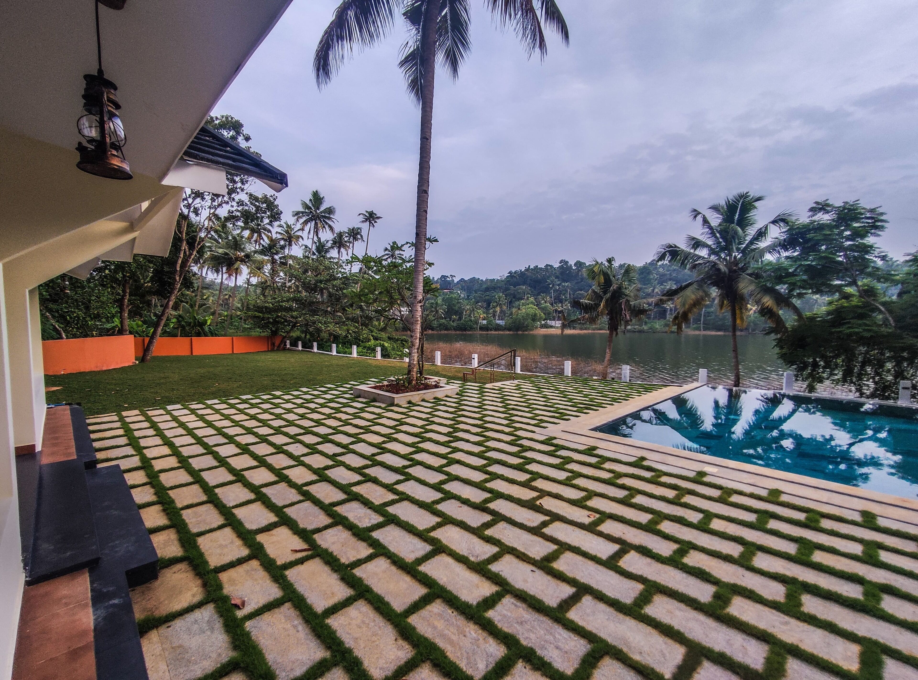 A pool area with a tiled deck, palm trees, and a view of a lake.