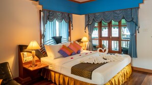 A hotel room with a bed, a nightstand, a lamp, a chair, and a window with curtains. - Sea Garden Resort - Haad Rin (Ko Pha-ngan)