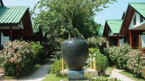 A garden pathway leading to a large decorative urn, surrounded by lush greenery and small potted plants. - Sea Garden Resort - Haad Rin (Ko Pha-ngan)