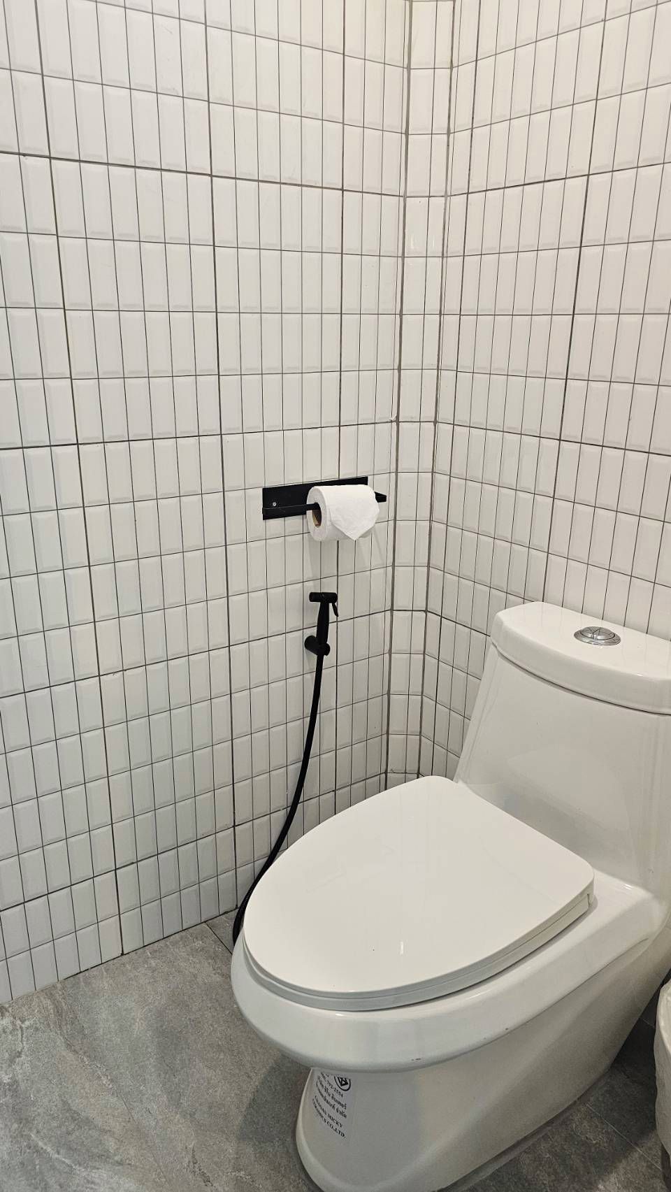 Ein Badezimmer mit Toilette, Toilettenpapierhalter und gefliesten Wänden.