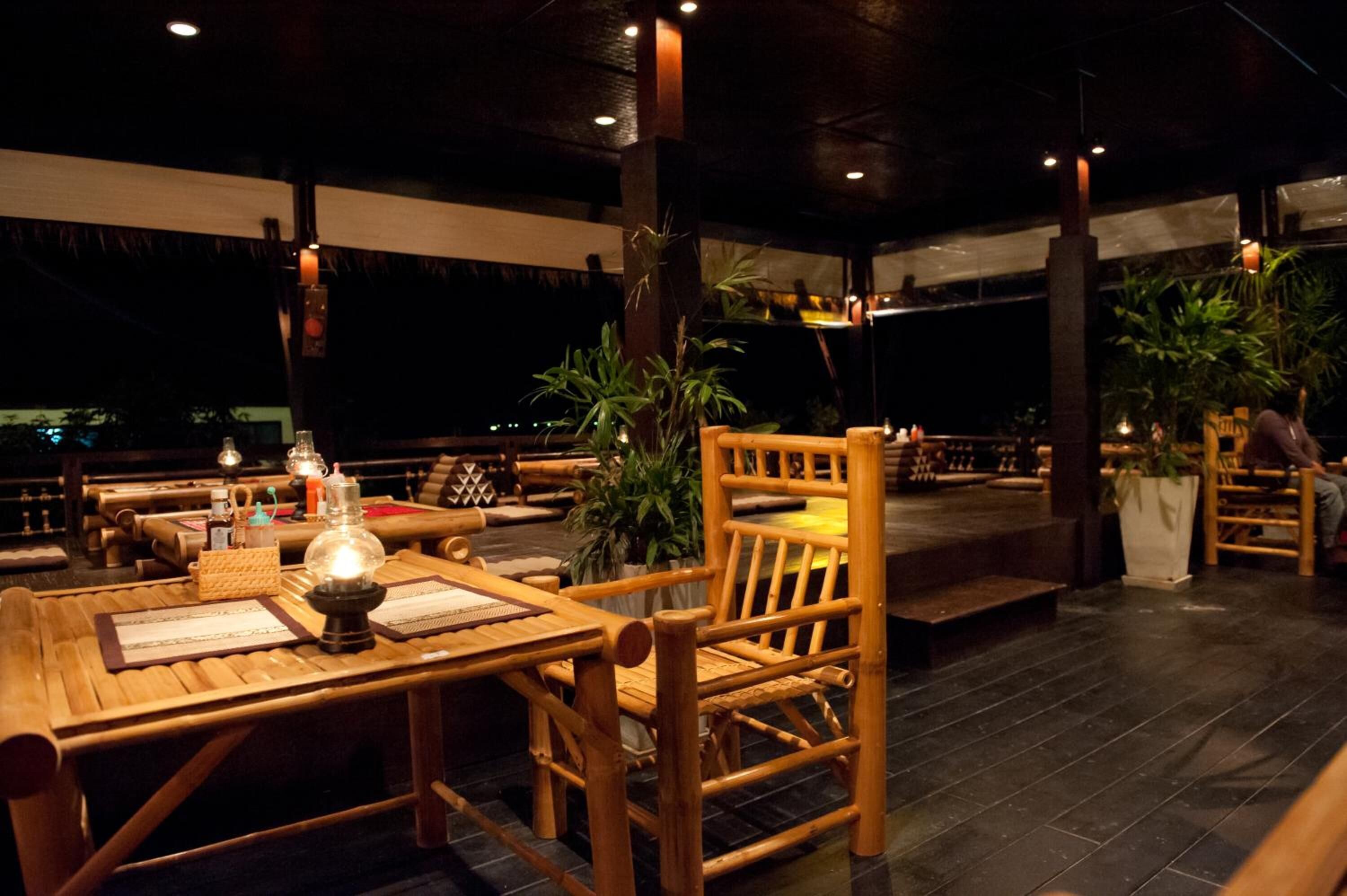 A restaurant with wooden furniture, tables, and chairs, and potted plants.