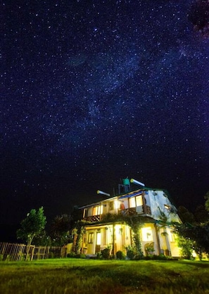 A house with a large window and a satellite dish under a starry night sky. - Emerald Trail (Nainital)