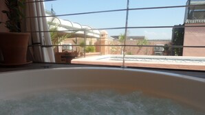 Ein Whirlpool mit Blick auf einen Pool und Gebäude im Hintergrund.