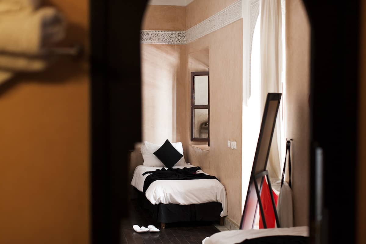 Un dormitorio con cama, espejo y un cuadro en la pared.